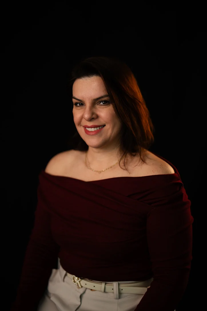 Patricia Kalisiensky sorrindo em um retrato com fundo escuro